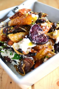 a white bowl filled with food sitting on top of a wooden table next to a fork