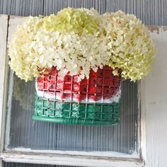 a vase filled with white and red flowers sitting on top of a window sill