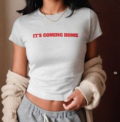 a woman wearing a t - shirt that says it's coming home on the chest