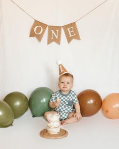 a baby is sitting on the floor in front of balloons and a one birthday banner