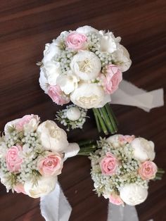 three bridal bouquets with pink and white flowers on them sitting on a table