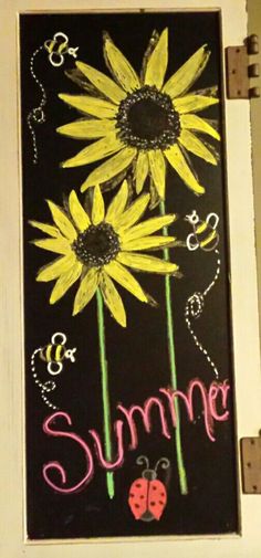 a chalkboard with sunflowers and ladybug drawn on it's side