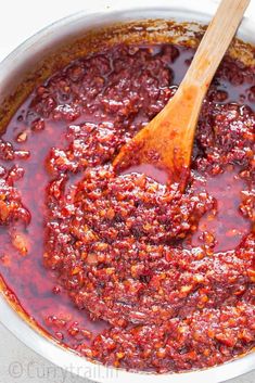 homemade schezwan sauce in a white bowl with a wooden spoon on the side