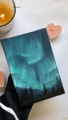 an acrylic painting of the northern lights with candles and tea light holders next to it