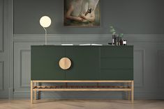 a green sideboard with a painting on the wall above it and a wooden shelf below