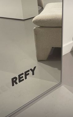 the reflection of a white chair in a mirrored wall with refy written on it