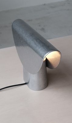 a silver lamp sitting on top of a table next to a white wall and floor