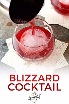 a glass filled with red liquid sitting on top of a table next to paper napkins