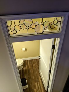 an overhead view of a bathroom door with stained glass over the toilet and sink area