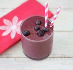 a smoothie in a glass with blueberries on top