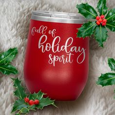 a red wine glass with the words, full of holiday spirit on it next to holly leaves