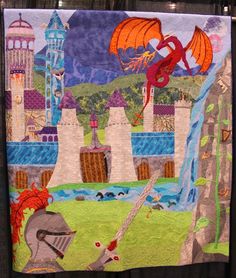 a quilted wall hanging with a red dragon on it's side and a castle in the background