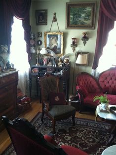 a living room filled with lots of furniture and paintings on the wall next to a window