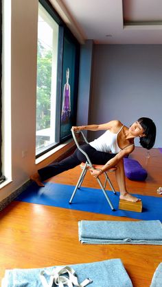 a woman is sitting on a chair doing yoga