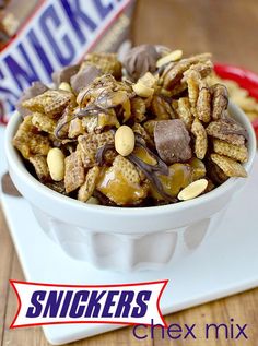 a bowl filled with nuts and chocolate on top of a table next to a bag of snickkers