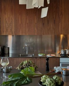 the kitchen counter is cluttered with vegetables and papers hanging from the hooks above it