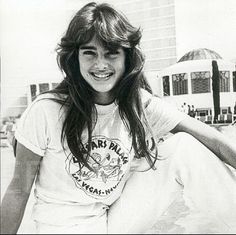 a young woman sitting on the ground with her legs crossed and smiling at the camera