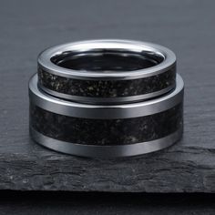 two wedding bands with black and white marble inlays on top of each other