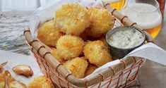 a basket filled with tater tots next to two glasses of beer and dipping sauce