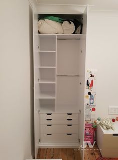 a white closet with drawers and clothes on it's shelves in a room next to a bed