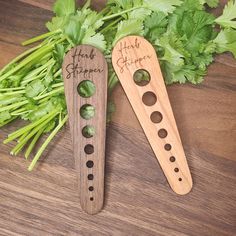 two wooden spoons with holes in them sitting on a table next to some parsley