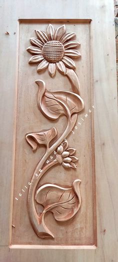 a wooden carving with flowers and leaves on it