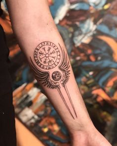 a person with a black and white tattoo on their arm holding a compass in one hand