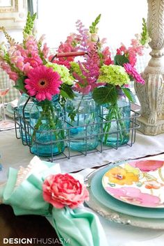 there are many flowers in the vases on the dining room table with plates and napkins