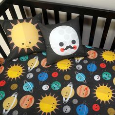 a black crib bed with space themed sheets and pillow cases on top of it