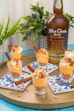 four desserts with cinnamon and whipped cream on a tray next to a bottle of booze