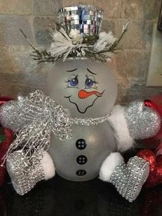 a snowman ornament sitting on top of a table with silver and red decorations