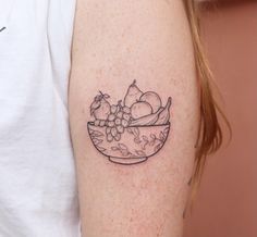 a woman's arm with a bowl of fruit tattoo on it