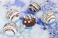 four chocolate covered desserts sitting on top of a blue and white table cloth with snow flakes