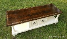 a wooden bench sitting on top of a grass covered field next to a white cabinet