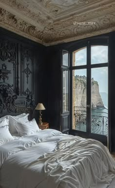 a bed with white sheets and pillows in a bedroom next to an open window overlooking the ocean