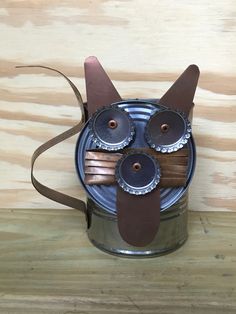 a tin can with an owl made out of metal cans and some brown leather straps