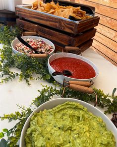 guacamole, salsa and tortilla chips on a table with other foods