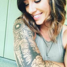 a woman with tattoos on her arm smiling