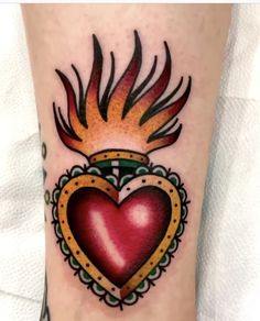 a heart tattoo on the leg with flames coming out of it and a crown in the middle