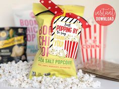 popcorn bag with red bow and candy bar wrapper sitting on top of it next to other snacks