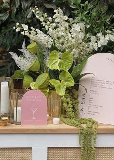 a table topped with flowers and candles next to a card holder on top of a wooden shelf