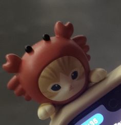 a cell phone with a little doll on top of it