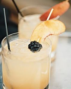 two glasses filled with drinks and garnished with fruit on the top one glass has an apple slice sticking out of it