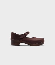 Mary Jane wooden clogs in dark brown nubuck leather stapled on a dark wooden base Flat Heel Clogs With Cushioned Footbed For Work, Cushioned Flat Heel Clogs For Work, Classic Closed Toe Clogs With Cushioned Footbed, Brown Low Heel Clogs With Removable Insole, Brown Clogs With Wooden Low Heel, Slip-on Clogs With Low Heel And Leather Sole, Slip-on Clogs With Rubber Sole Low Heel, Slip-on Clogs With Low Heel, Classic Slip-on Clogs With Buckle