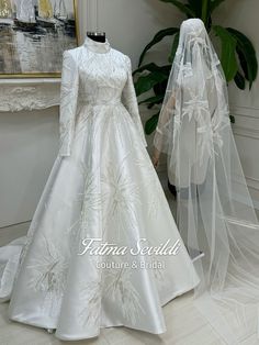 two white wedding gowns on mannequins in front of a painting