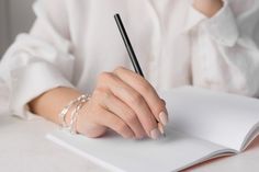 a woman holding a pen and writing on a book