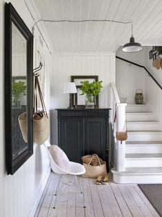 an entryway with white walls and wood flooring, hanging baskets on the wall