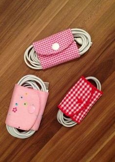 three cell phones are laying on the floor next to cords and charging devices, with one being plugged in