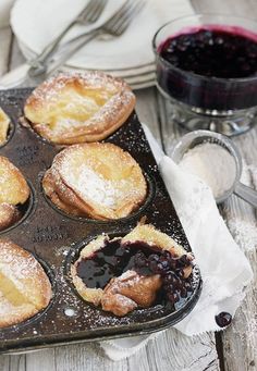 blueberry muffins in a muffin tin with powdered sugar