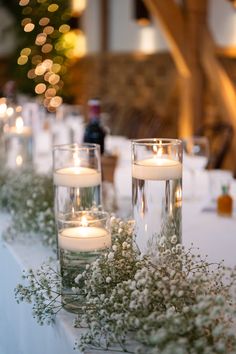 three candles are sitting on a table with flowers and greenery in front of them